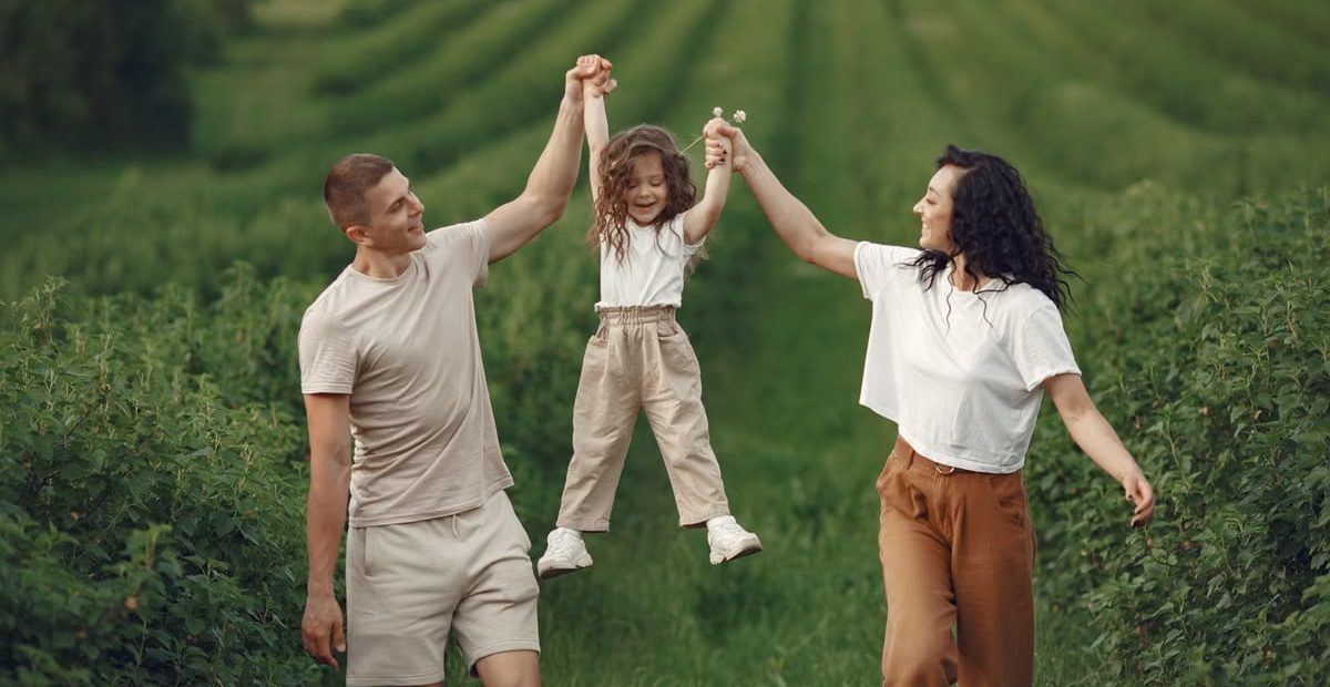 Joyful family moment in a green field during summer, capturing love and playfulness.
