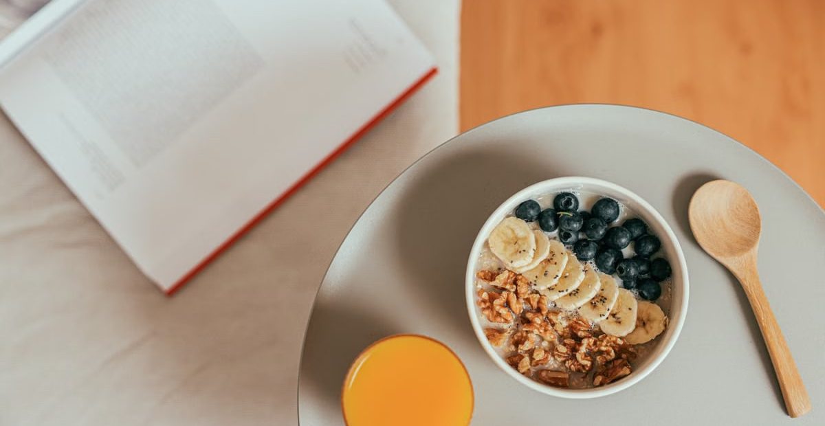 Top view of healthy breakfast with oatmeal, fresh fruit, and orange juice on a tray.
